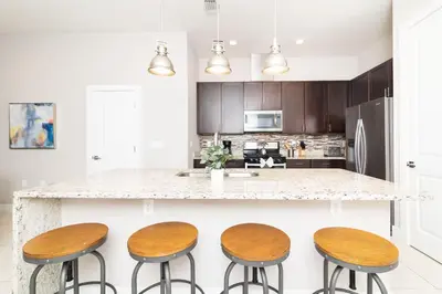 a kitchen with three wooden stools at a counter at Sunrise in Kissimmee - Near Disney World in Orlando