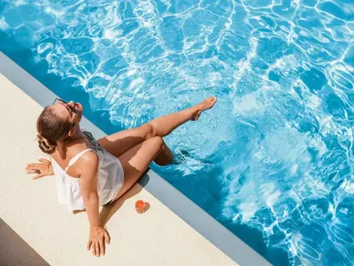 a woman sitting on the edge of a swimming pool at Candlewood Suites Orlando North - Winter Park by IHG in Orlando