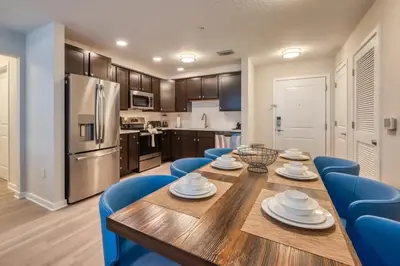a kitchen and dining room with a wooden table and blue chairs at Conforto e Estilo | 3Q Piscina & Resort in Orlando