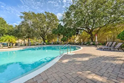 a swimming pool with chairs and trees at 4 Mi to WDW Sleek Townhome with Community Pool! in Kissimmee