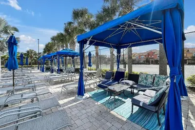 a group of chairs and blue umbrellas on a patio at Fully Equipped Comfortable Townhouse in Kissimmee