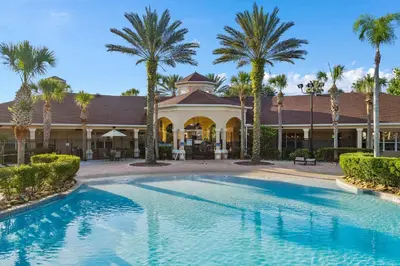 a swimming pool in front of a building with palm trees at Disney Retreat w/ Wizard & Galaxy Rooms in Orlando