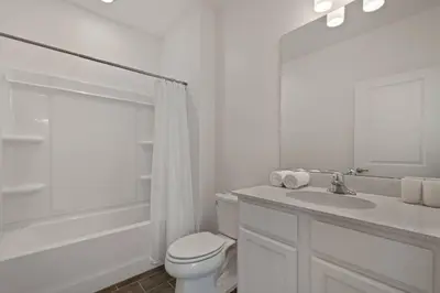 a white bathroom with a toilet and a sink at Magical 15-Bedroom Villa | Game Room, Theater & More! in Kissimmee