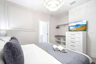 a white bedroom with a bed and a flat screen tv at Themed Kids' Rooms, Pool & Game Loft Near Disney in Kissimmee