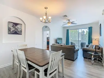 a dining room and living room with a table and chairs at Windsor Hills Modern 3BR Condo with Resort Amenities in Orlando