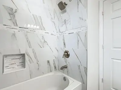 a bathroom with white marble walls and a tub at Windsor Hills Modern 3BR Condo with Resort Amenities in Orlando