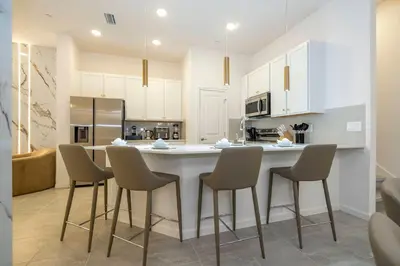 a kitchen with white cabinets and a large island with chairs at Paradiso Grande 5 Bed New Townhome - 10329 in Orlando