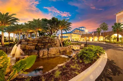 a park with a waterfall and palm trees in front of a building at Universal's Loews Sapphire Falls Resort in Orlando