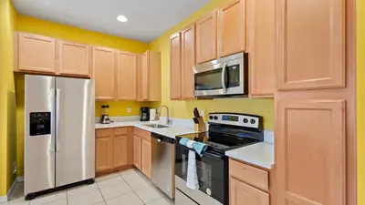 a kitchen with wooden cabinets and stainless steel appliances at SHVCK1 - Coral Cay Resort #1 - 4 Bedroom Townhouse in Kissimmee