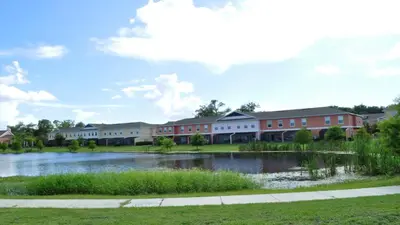 a building with a lake in front of it at SHVCK3 - Coral Cay Resort #3 - 4 Bed 3 Baths Townhome in Kissimmee