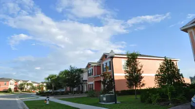 a building with trees in front of a street at SHVCK4 - Coral Cay Resort #4 - 4 Bed 3 Baths Townhome in Kissimmee