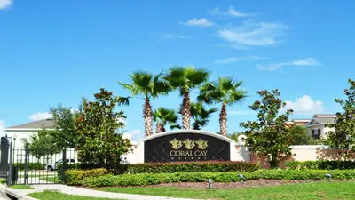 a sign in front of a building with palm trees at SHVCK4 - Coral Cay Resort #4 - 4 Bed 3 Baths Townhome in Kissimmee