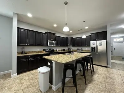 a kitchen with black cabinets and a island with bar stools at SHVPP1 - Paradise Palms #1 - 6 Bed 5 Baths Villa in Kissimmee