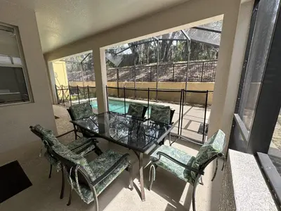 a balcony with a glass table and chairs and a pool at SHVPP1 - Paradise Palms #1 - 6 Bed 5 Baths Villa in Kissimmee