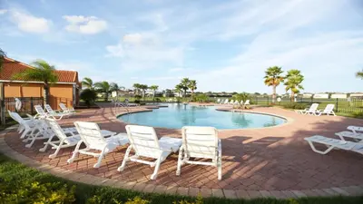 a patio with white chairs and a swimming pool at SHVCC1 - Crystal Cove #1 - 7 Bed 4.5 Baths Villa in Kissimmee