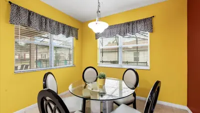 a dining room with yellow walls and a glass table and chairs at SHVCC2 - Crystal Cove #2 - 7 Bed 4.5 Baths Villa in Kissimmee