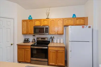 a kitchen with wooden cabinets and a white refrigerator at Peaceful Getaway in Windsor Hills in Orlando