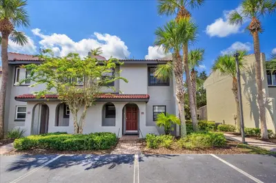 a white house with palm trees in front of it at Cozy Townhome in Fantasy World Near Parks in Kissimmee