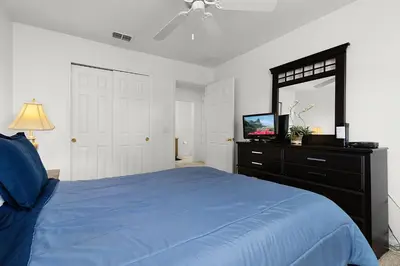 a bedroom with a blue bed and a dresser with a mirror at Spacious Lakefront Townhouse 10 Mins To Disney in Kissimmee