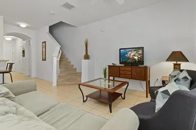 a living room with a couch and a tv at Spacious Lakefront Townhouse 10 Mins To Disney in Kissimmee