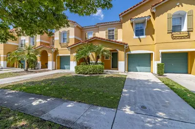 a large yellow house with two garage doors at Spacious Lakefront Townhouse 10 Mins To Disney in Kissimmee