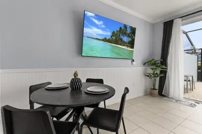 a dining room with a table and a tv on the wall at Cozy 3Br Villa With Pool Disney Nearby in Orlando