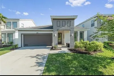 a large white house with a garage at Luxury Family Villa With Pool & Bbq Near Disney! in Kissimmee