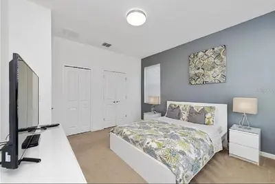 a bedroom with a bed and a flat screen tv at Luxury Family Villa With Pool & Bbq Near Disney! in Kissimmee