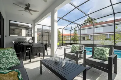 a patio with a table and chairs and a pool at Brand New 12 Bedrooms Single Family Paradiso 85HI in Orlando