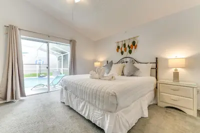 a white bedroom with a bed and a sliding glass door at 4 Mi to Disney Home with Pool Table, Outdoor Oasis! in Orlando