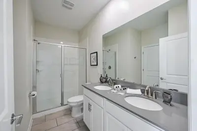 a bathroom with two sinks and a shower and a toilet at Casa9 quartos p/ família+Temas c/ piscina in Kissimmee