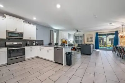 a large kitchen with white cabinets and appliances at Casa9 quartos p/ família+Temas c/ piscina in Kissimmee
