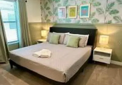 a bedroom with a large bed with two lamps and a window at 3231 ED - The Hub Modern 3BR in Kissimmee