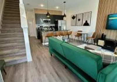 a living room with a green couch and a kitchen at 3231 ED - The Hub Modern 3BR in Kissimmee