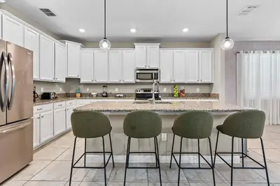 a kitchen with white cabinets and a large island with bar chairs at Amazing 06 Bedrooms3 BathSleeps 14 in Kissimmee