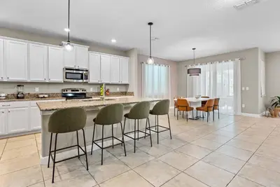a kitchen with white cabinets and a table with chairs at Amazing 06 Bedrooms3 BathSleeps 14 in Kissimmee