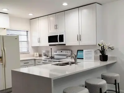 a kitchen with white cabinets and a kitchen island with stools at Family vacation Villa in Fantasy World Resort - Minutes from Disney in Kissimmee