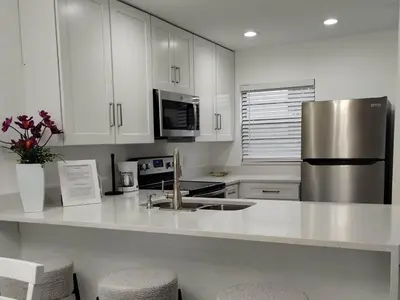 a kitchen with white cabinets and a stainless steel refrigerator at Family Townhouse with Waterpark - Minutes from Disney in Kissimmee