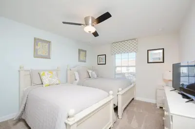 two beds in a bedroom with a ceiling fan at Casa 4Q Piscina Privativa — Storey Lake Resort in Kissimmee