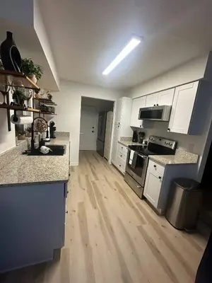 a kitchen with white cabinets and a wooden floor at Historic Retreat on Eola + Private Hot Tub + Grill in Orlando