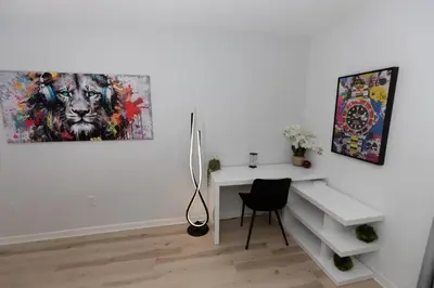 a white room with a desk and paintings on the wall at Historic Retreat on Eola + Private Hot Tub + Grill in Orlando
