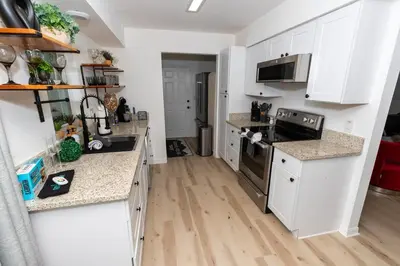 a kitchen with white cabinets and a wooden floor at Eola Retreat Private Hot Tub with Grill in Orlando