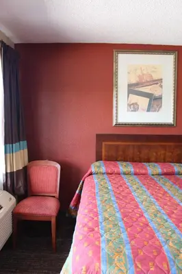 a bedroom with a bed and a chair at Oak Ridge Inn in Kissimmee
