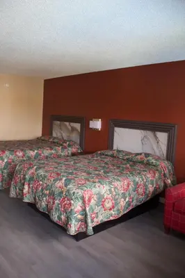 a hotel room with two beds and a red wall at Oak Ridge Inn in Kissimmee