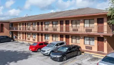 a building with cars parked in a parking lot at Oak Ridge Inn in Kissimmee