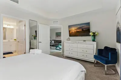 a white bedroom with a bed and a blue chair at Beautiful Lakeview Retreat Near Disney in Kissimmee