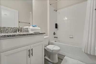 a white bathroom with a toilet and a bath tub at 6 Bedrooms 5 Bathrooms Storey Lake 4763Kc in Kissimmee