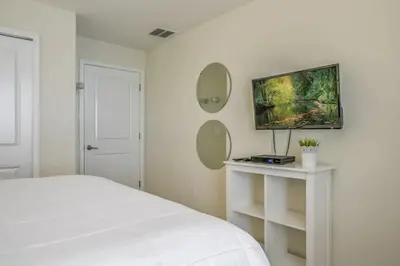 a white bedroom with a bed and two mirrors at Casa 4 Quartos c/ Piscina – 10 Min da Disney in Kissimmee