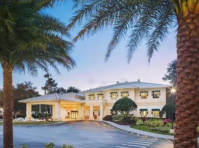 a large white building with palm trees in front of it at Sheraton Vistana Resort One Bedroom Apartment in Orlando