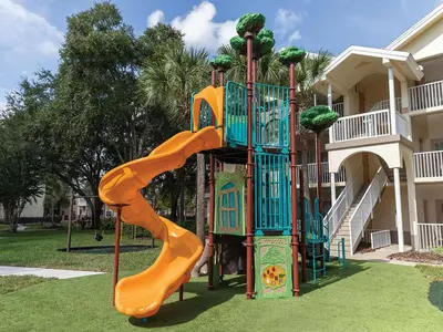 a playground with an orange slide in a yard at Sheraton Vistana Resort Two Bedroom Apartment with Resort Access in Orlando